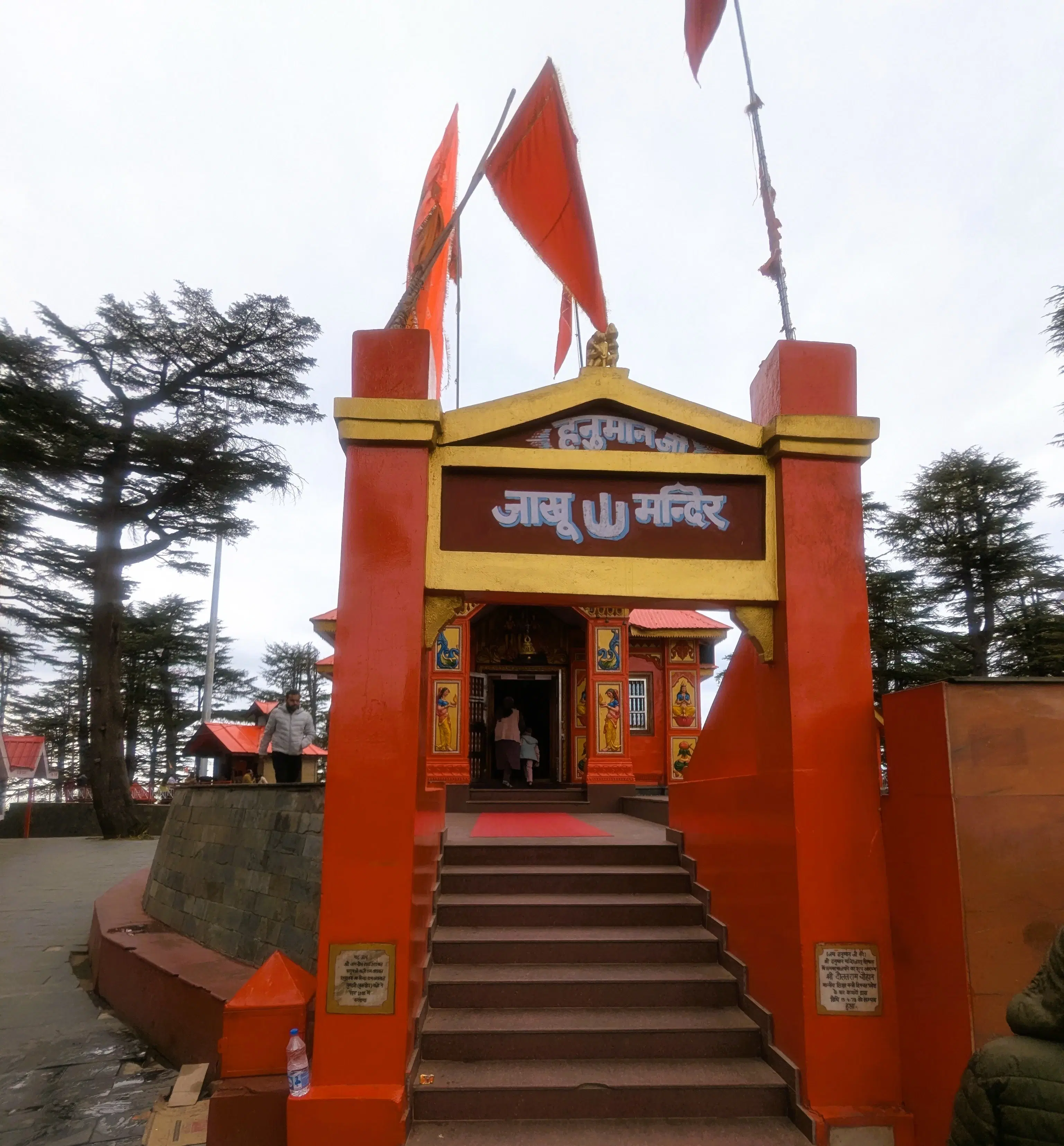Red and yellow entrance to Jakhoo Temple among deodar trees in Shimla