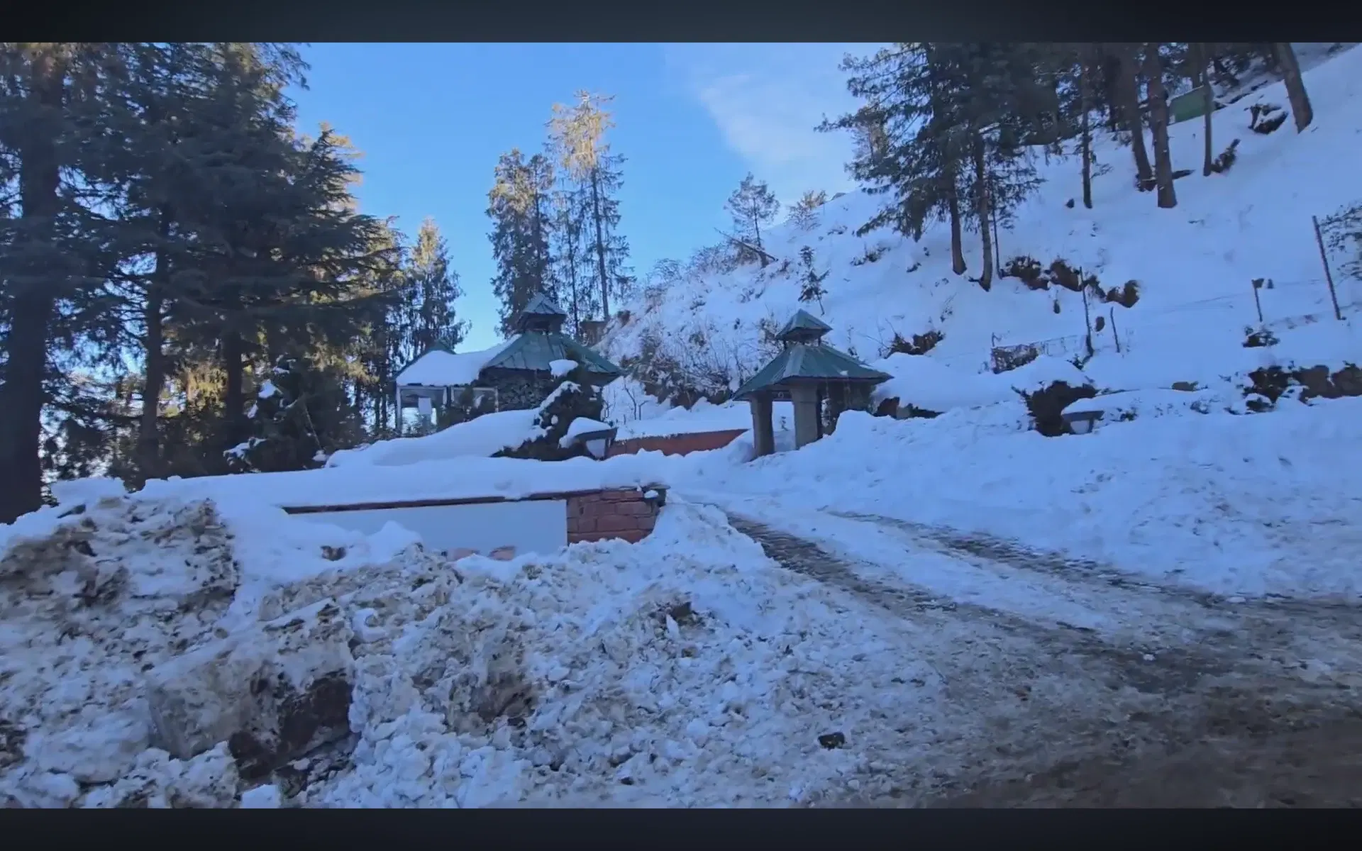 Snow-covered road and forest hillside in Kufri near Shimla