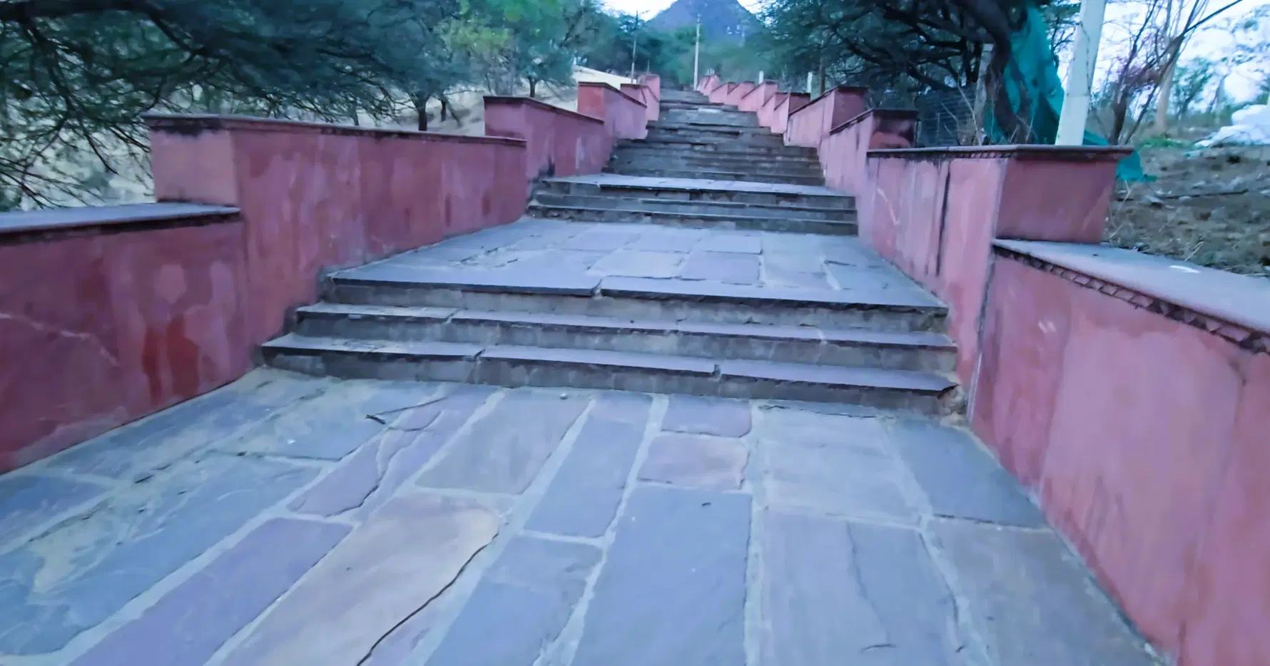 Stone steps with pink walls on the uphill route to Savitri Mata Temple in Pushkar