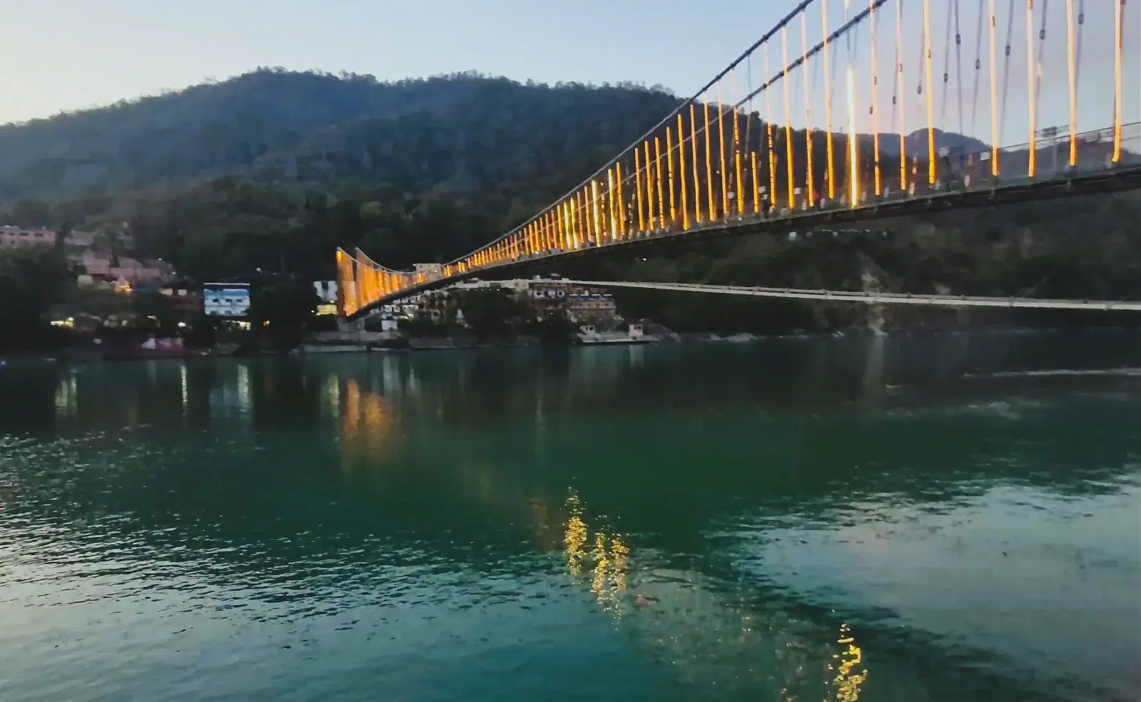Evening view of Ram Jhula suspension bridge over the sacred Ganga River with Himalayan foothills, Rishikesh