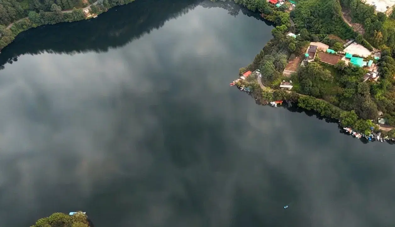 Calm nine-cornered Naukuchiatal lake surrounded by forested hills near Bhimtal, Nainital