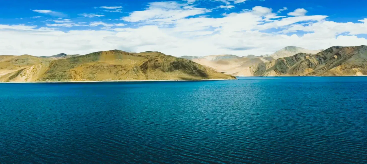 Pangong Tso's shifting turquoise-blue waters reflecting snowy mountains in Ladakh — one of India's most iconic landscapes