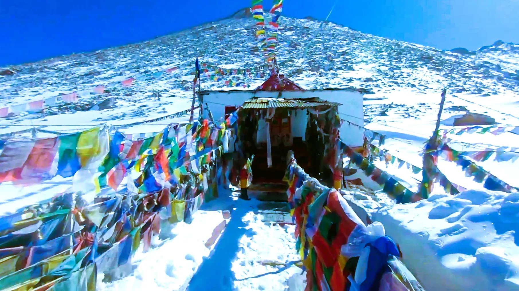 Chang La Pass at 5,360 m with Buddhist stupa, prayer flags, and Chang La Baba temple — gateway to Pangong Lake from Leh