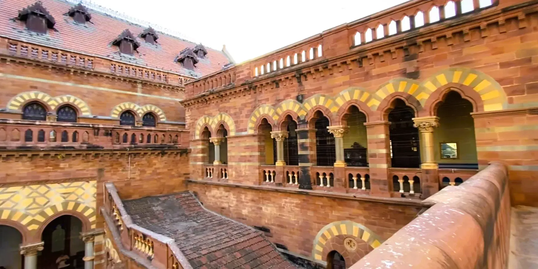 Striped arches and red-stone courtyard inside Prag Mahal in Bhuj