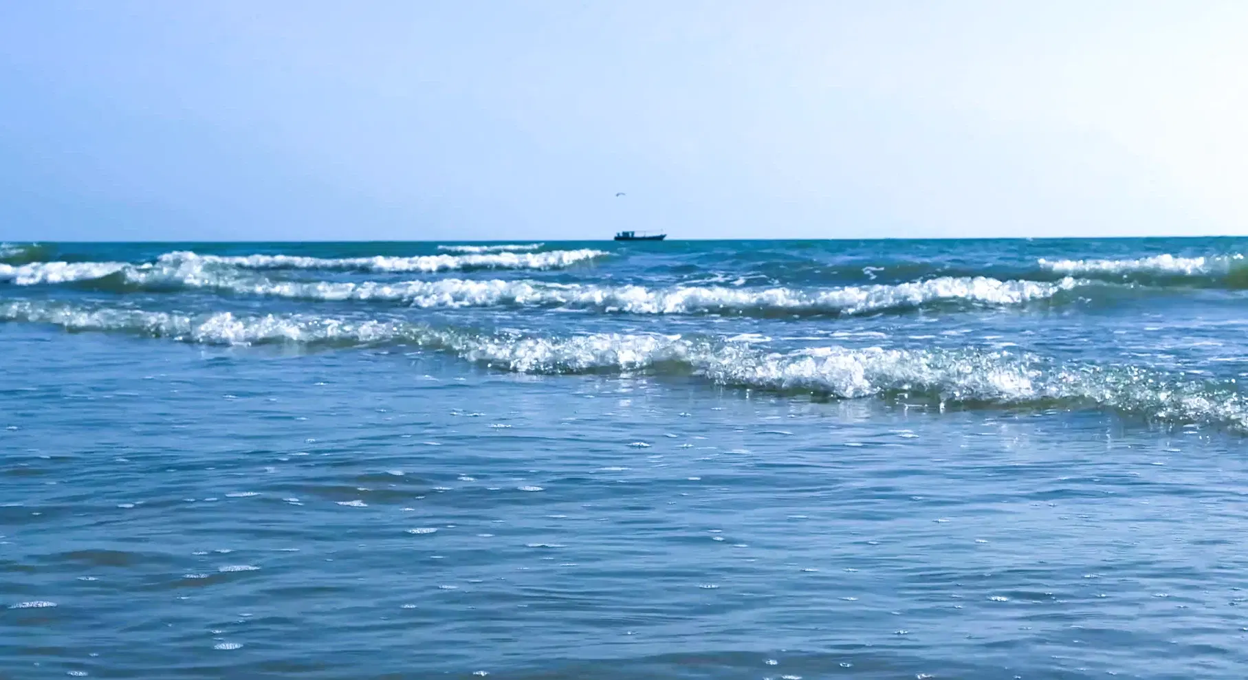 Arabian Sea waves and a fishing boat at Mandvi Beach in Kutch